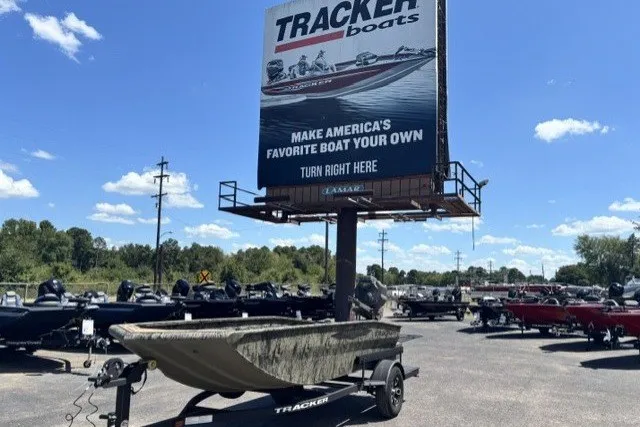 The Image of Tracker Grizzly 1650 T Prairie Wings Edition boat displayed outdoors under a Tracker Boats billboard. - 0