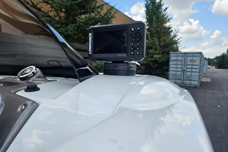 Slide: The Image of Lowrance device mounted on a 2026 Tahoe 1950 boat, outdoors with trees and containers. - 2