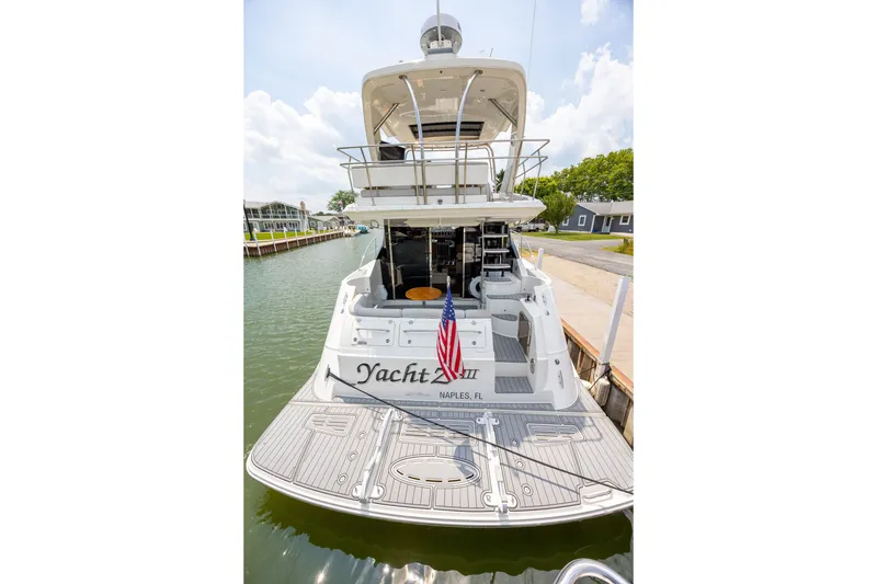 Slide: The Image of 2017 Sea Ray Fly 510 yacht docked, rear view with American flag, sunny day. - 2