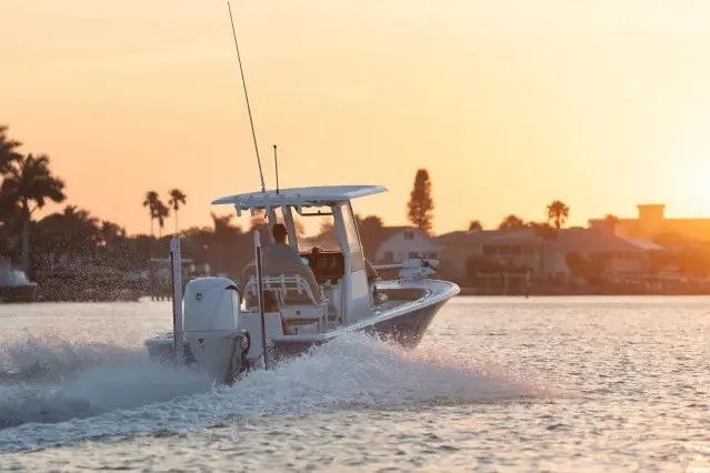 Slide: The Image of 2027 Sportsman Masters 247OE Bay Boat cruising at sunset on a serene waterway. - 2