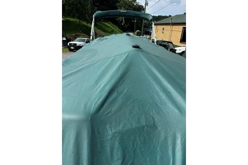 Slide: The Image of Covered 2005 Godfrey SANPAN 2500 boat with green tarp in outdoor setting. - 16