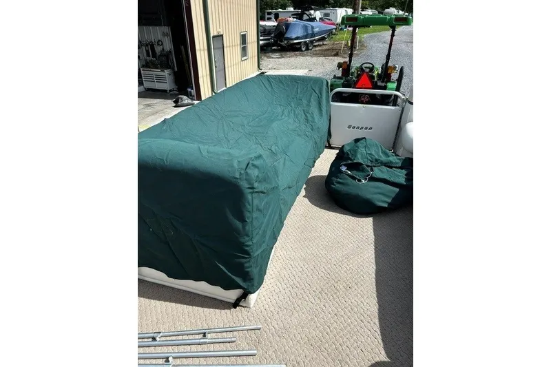 Slide: The Image of Covered 2005 Godfrey SANPAN 2500 boat with green tarp, outdoor setting. - 15