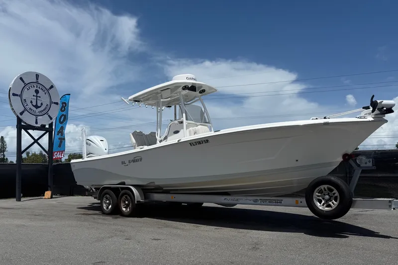 Slide: The Image of 2019 Blue Wave 2800 Pure Hybrid boat on trailer at dealership under clear sky. - 12