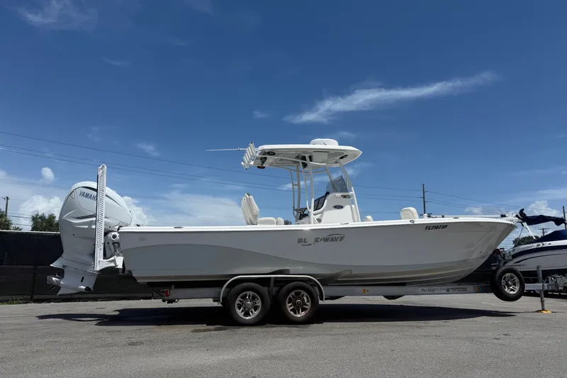 Slide: The Image of 2019 Blue Wave 2800 Pure Hybrid boat on trailer under clear blue sky. - 10