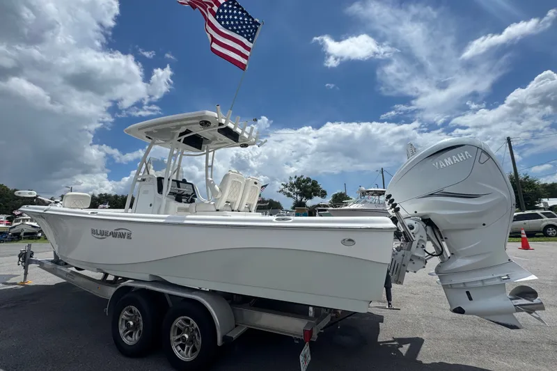 Slide: The Image of 2019 Blue Wave 2800 Pure Hybrid boat with Yamaha engine, American flag, and cloudy sky. - 3