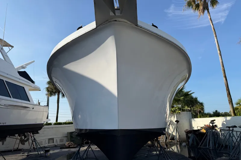 Slide: The Image of 1967 Hatteras 41 Convertible boat on dry dock, viewed from the front, with palm trees nearby. - 19