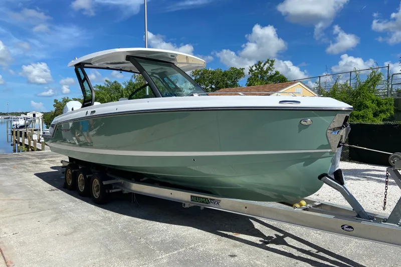 The Image of 2027 Monterey Elite 30 OB boat on trailer, parked outdoors under a clear blue sky. - 1