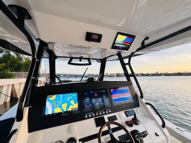 Slide: The Image of 2024 Regulator 41 boat cockpit with advanced navigation displays and steering wheel, docked by the water. - 30