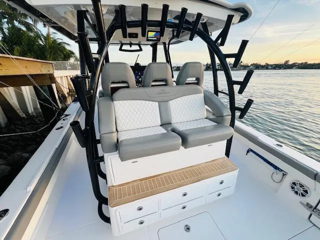 Slide: The Image of 2024 Regulator 41 boat interior with cushioned seating and rod holders by the water. - 32