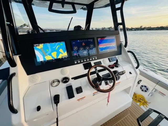 Slide: The Image of 2024 Regulator 41 boat dashboard with advanced navigation screens and controls, overlooking serene waters. - 29