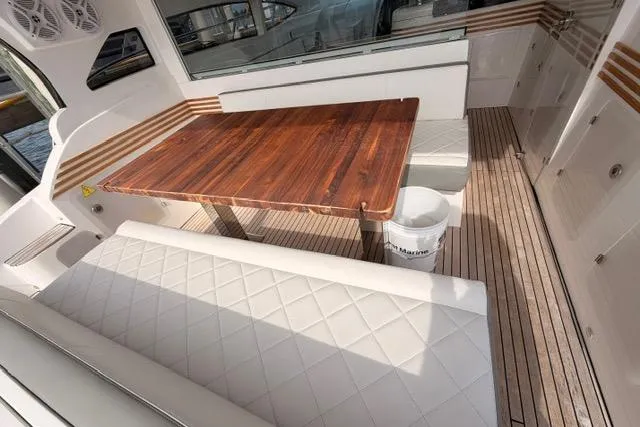 Slide: The Image of Luxurious seating area on 2025 Real 40 HT Luxury yacht with wooden table and white cushions. - 24