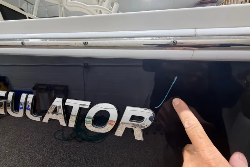 Slide: The Image of 2015 Regulator 23 boat with scratch on hull, finger pointing at damage. - 49