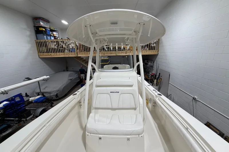Slide: The Image of 2015 Regulator 23 boat in indoor storage, featuring white seating and T-top. - 22