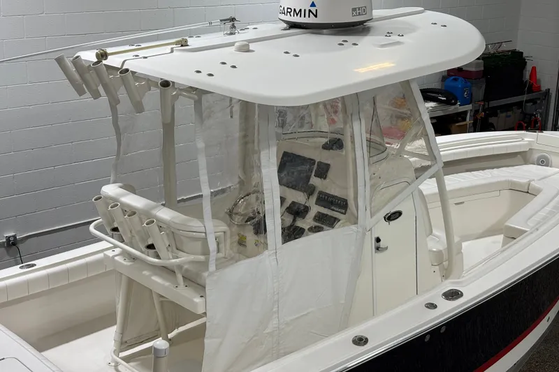 Slide: The Image of 2015 Regulator 23 boat with Garmin radar, enclosed helm, and rod holders in a garage. - 25