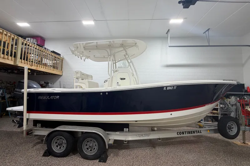 Slide: The Image of 2015 Regulator 23 boat on trailer in a garage, featuring a sleek navy and white design. - 4