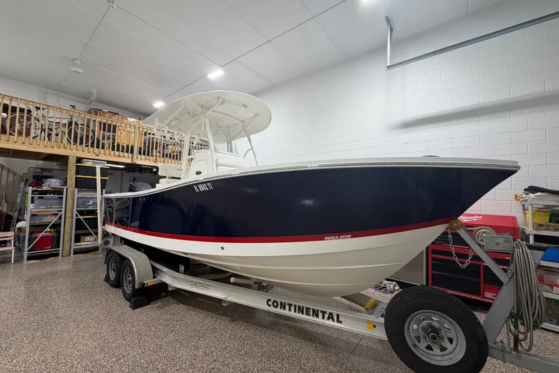 Slide: The Image of 2015 Regulator 23 boat on trailer in a garage with storage shelves. - 5