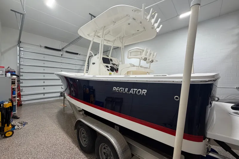 Slide: The Image of 2015 Regulator 23 boat in garage, blue hull with red stripe, on trailer. - 7