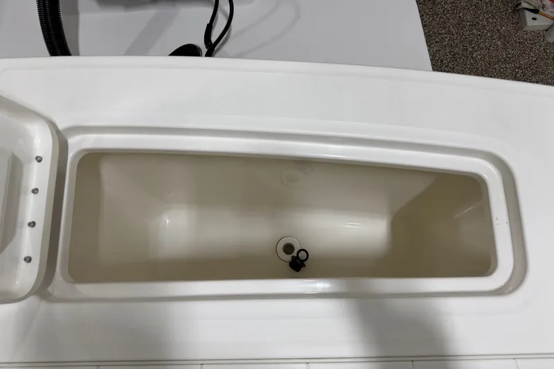 Slide: The Image of 2015 Regulator 23 boat storage compartment, white interior, open lid view. - 38