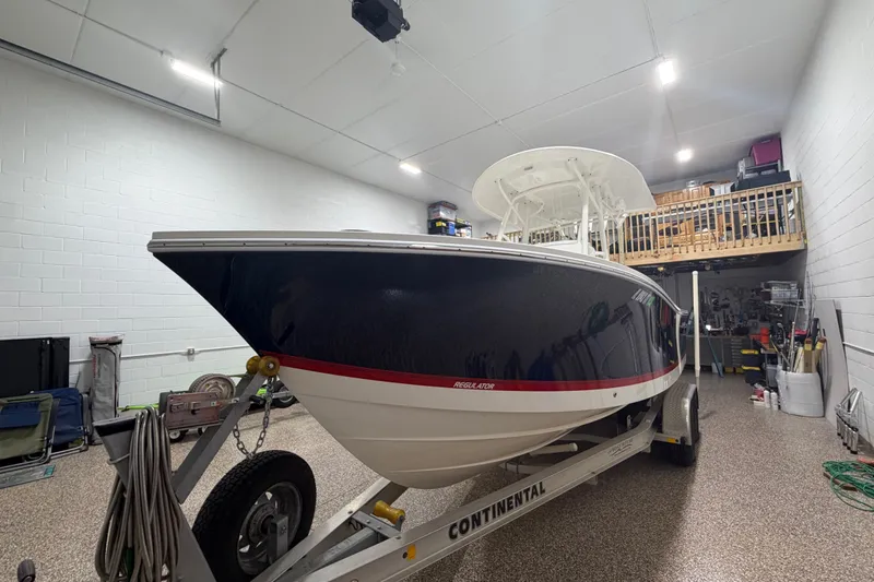 Slide: The Image of 2015 Regulator 23 boat on trailer in a spacious indoor garage. - 8