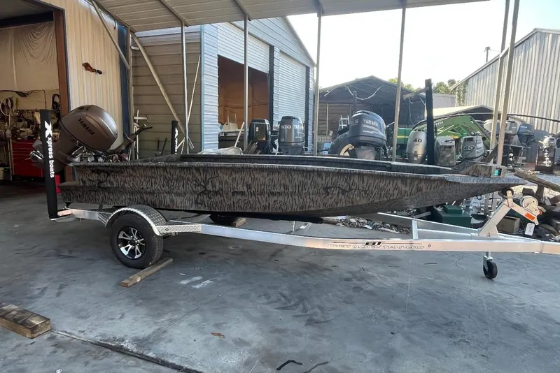The Image of 2027 Xpress VX16DB boat on trailer in a covered storage area. - 1