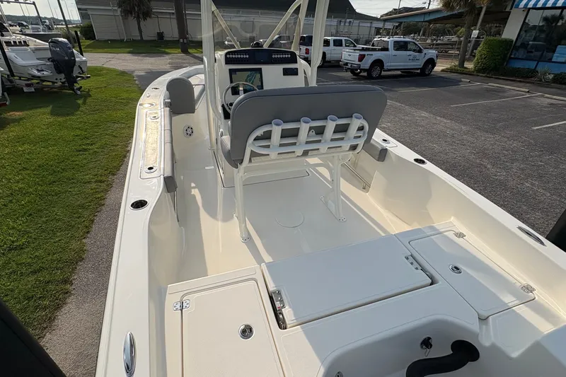 Slide: The Image of 2027 Pioneer 220 Bay Sport boat interior with seating and console, parked outdoors. - 10
