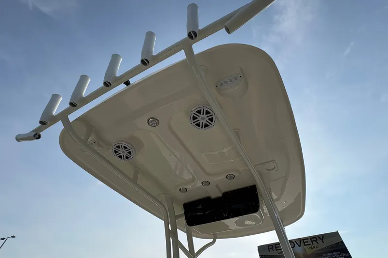Slide: The Image of 2027 Pioneer 220 Bay Sport boat top view with rod holders and speakers against blue sky. - 18