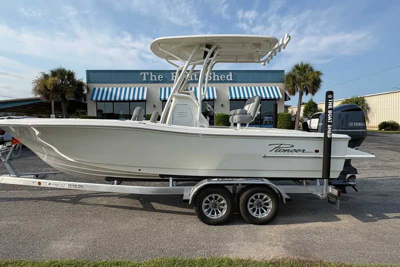 The Image of 2027 Pioneer 220 Bay Sport boat on trailer outside dealership. - 1