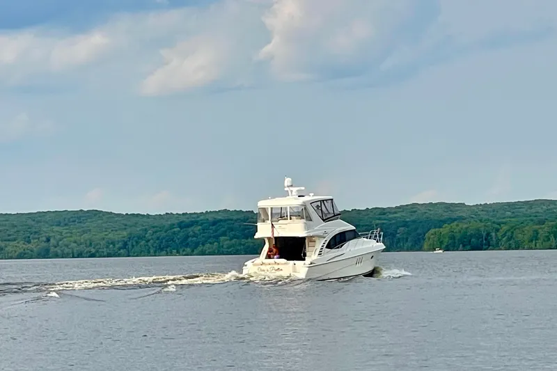 Slide: The Image of 2008 Silverton 52 Ovation yacht cruising on a serene lake with lush green shoreline. - 10