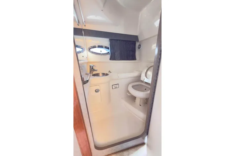 Slide: The Image of 2005 Formula 330 Sun Sport boat bathroom with sink, toilet, and porthole windows. - 7