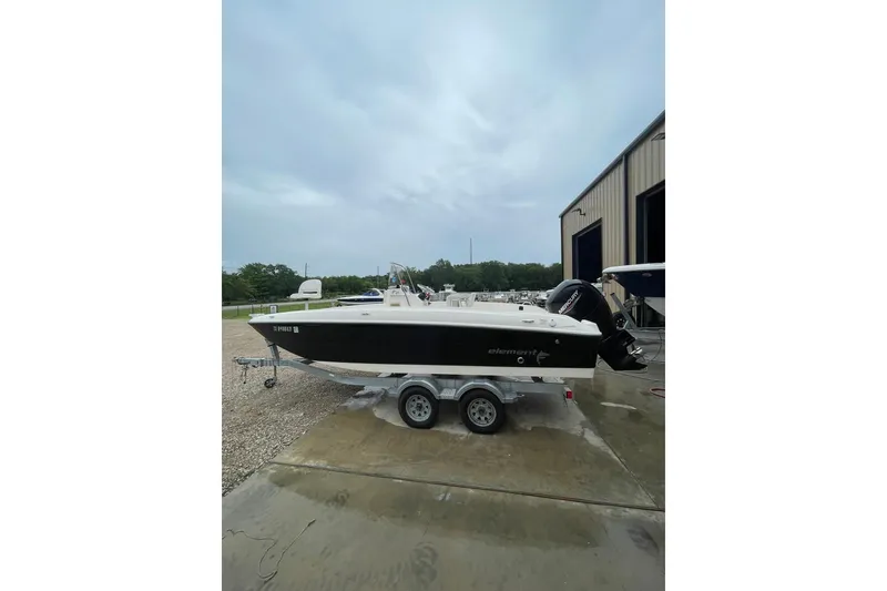 The Image of 2021 Bayliner Element F21 boat on trailer, parked outside a warehouse. - 1