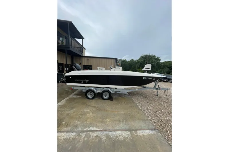 Slide: The Image of 2021 Bayliner Element F21 boat on trailer, parked outdoors near a building. - 2