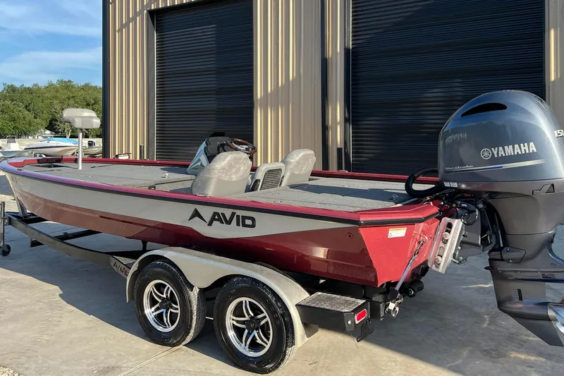 Slide: The Image of 2024 Avid 20 XB boat with Yamaha motor, parked outside a building. - 5