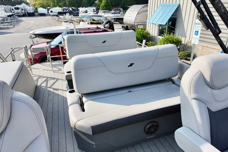 Slide: The Image of 2023 Starcraft CX 25 DL boat interior with plush seating in a marina setting. - 9