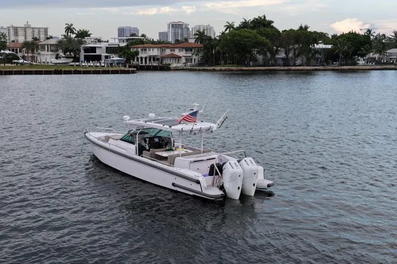The Image of 2024 Axopar 37 Sun-Top boat on calm water near waterfront homes. - 1