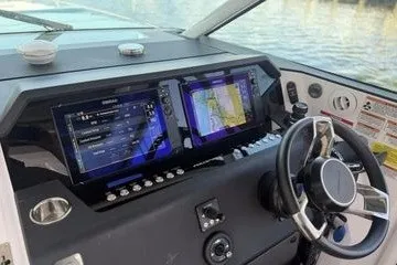 Slide: The Image of 2024 Axopar 37 Sun-Top dashboard with dual navigation screens and steering wheel. - 4