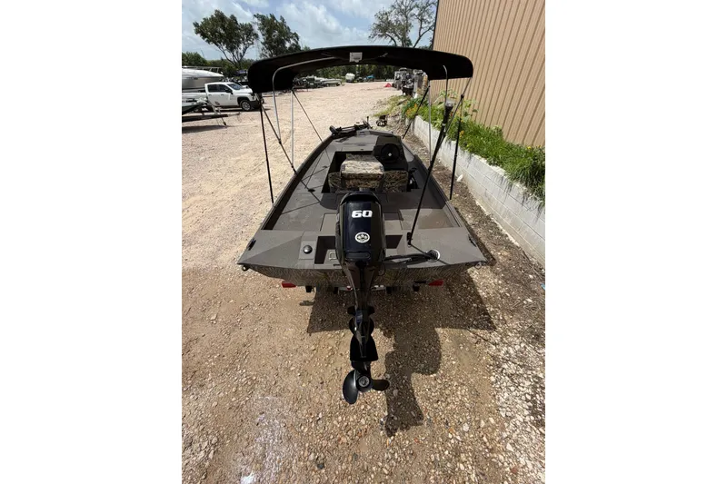 Slide: The Image of 2024 Alweld 1856 Invader boat with outboard motor, parked on gravel near a building. - 7