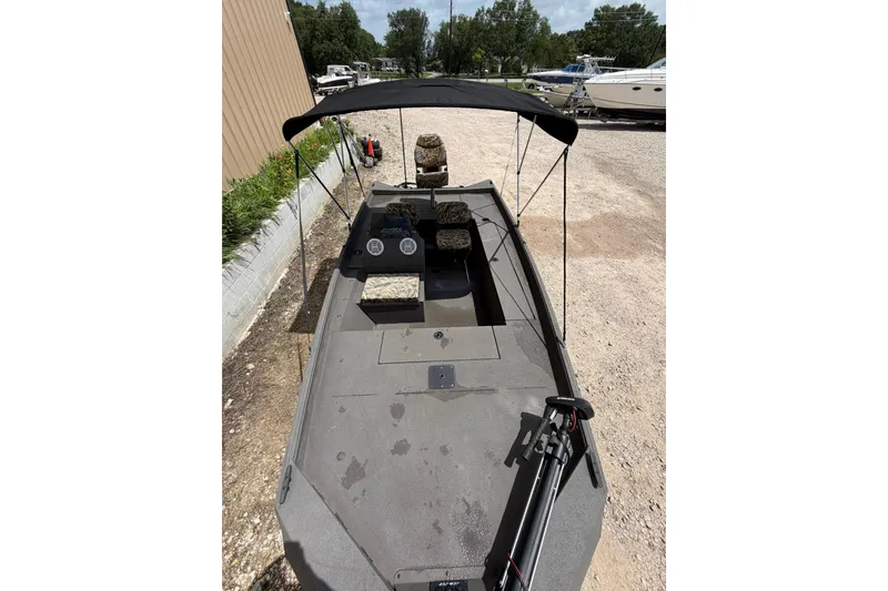 Slide: The Image of 2024 Alweld 1856 Invader boat with canopy, parked outdoors on gravel. - 6