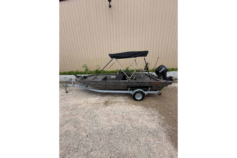 Slide: The Image of 2024 Alweld 1856 Invader boat with canopy on trailer, parked outdoors. - 2