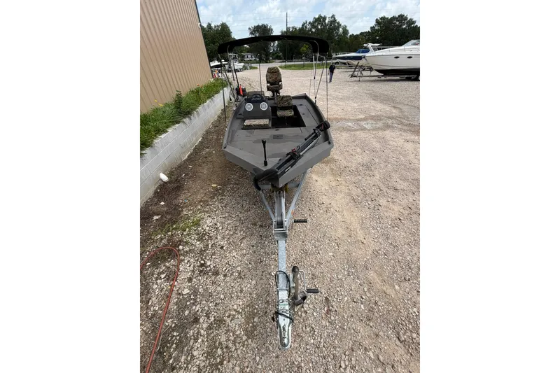 Slide: The Image of 2024 Alweld 1856 Invader boat on trailer, parked outdoors near other boats. - 4