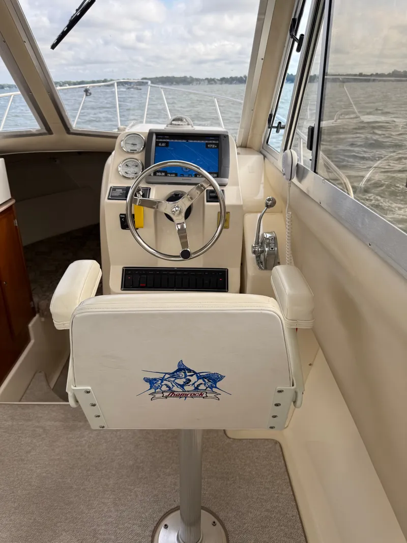 Slide: The Image of The cockpit of a 2008 Shamrock 270 Mackinaw with a helm station and a cushioned seat. - 8