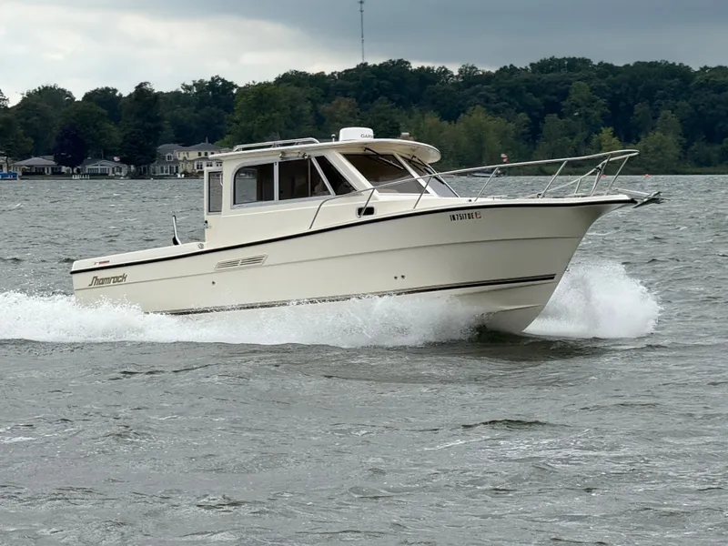 Slide: The Image of A 2008 Shamrock 270 Mackinaw speeds across the water, surrounded by trees and houses. - 17