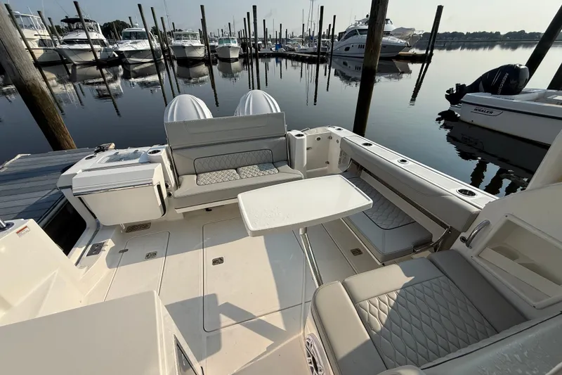 Slide: The Image of 2026 Pursuit DC 326 Dual Console boat interior at marina, featuring seating and table. - 11