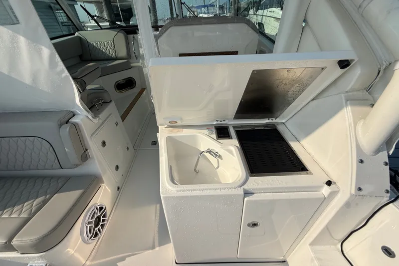 Slide: The Image of 2026 Pursuit DC 326 Dual Console boat interior with sink and seating area. - 9