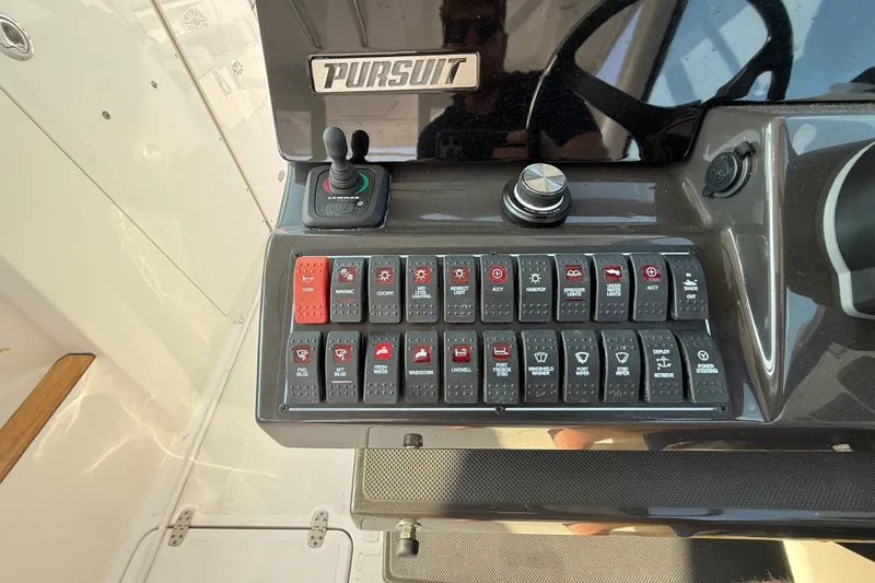 Slide: The Image of Control panel of 2026 Pursuit DC 326 Dual Console boat with labeled switches. - 17