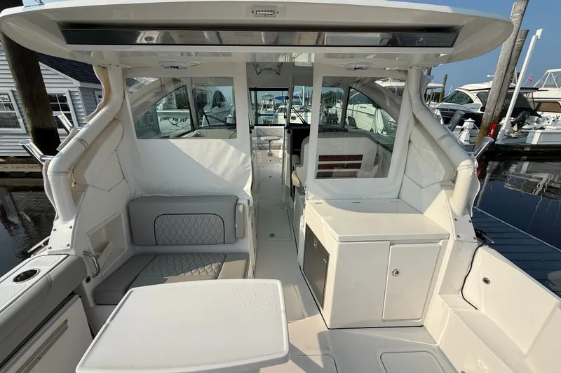 Slide: The Image of 2026 Pursuit DC 326 Dual Console boat interior with seating and storage, docked at marina. - 8