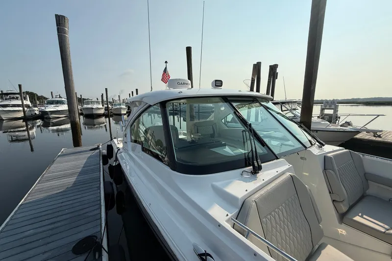 Slide: The Image of 2026 Pursuit DC 326 Dual Console boat docked at marina, clear sky, calm water. - 5