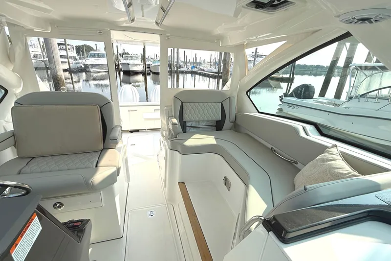 Slide: The Image of Interior of a Pursuit DC 326 Dual Console with sleek seating and marina view. - 13
