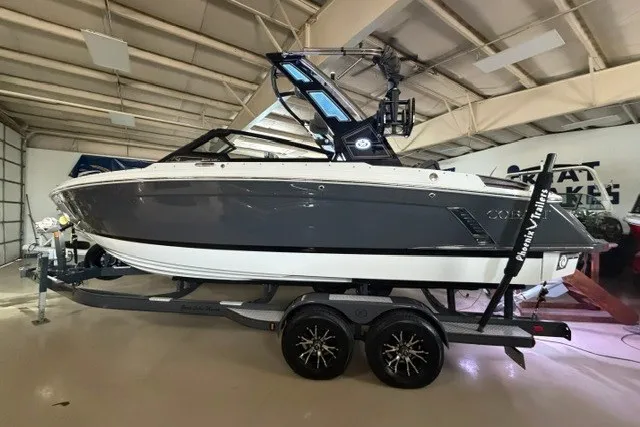 The Image of 2023 Cobalt R4 Surf boat in a showroom, featuring sleek design and modern trailer. - 1