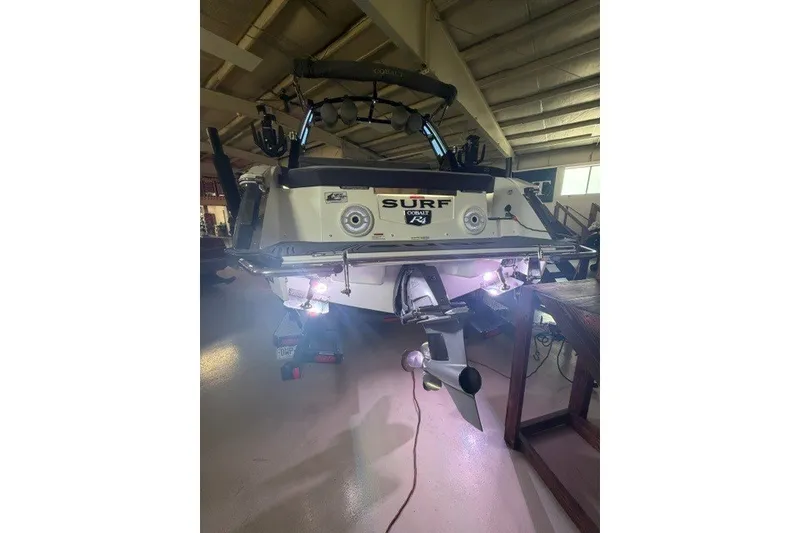 Slide: The Image of 2023 Cobalt R4 Surf boat in a garage, rear view with illuminated propeller. - 6