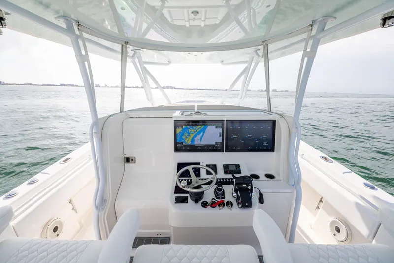 Slide: The Image of 2020 Contender 44 Fisharound helm with dual screens, steering wheel, and ocean view. - 28